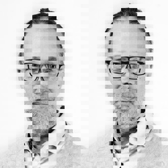 Professor Dr Jens Scherpe in black and white, wearing glasses in front of a plain background.