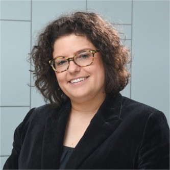 Patricia Marleau in glasses, a black jacket and top, in front of a geometric glass background